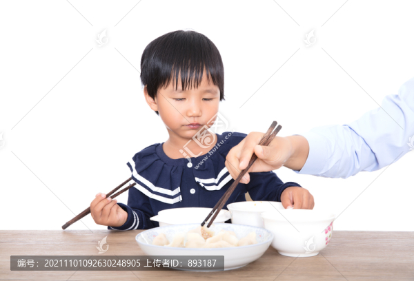 中國(guó)小姑娘在媽媽的監(jiān)督下吃餃子