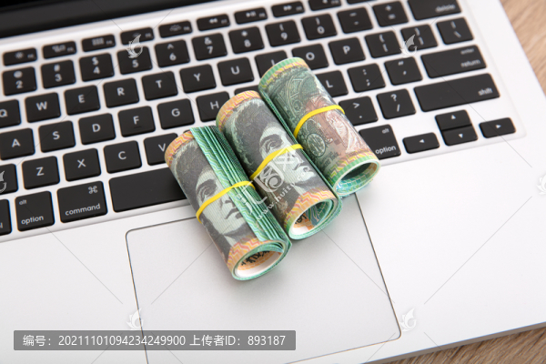 電腦鍵盤上放著三卷澳元鈔票