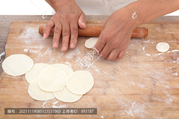 手拿搟面杖在砧板上搟餃子皮