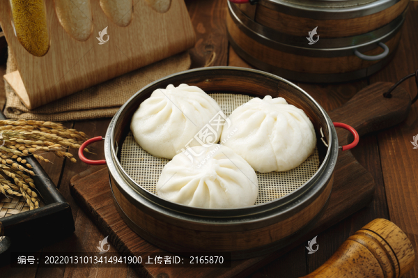 深色木板背景上擺放的蒸籠包子