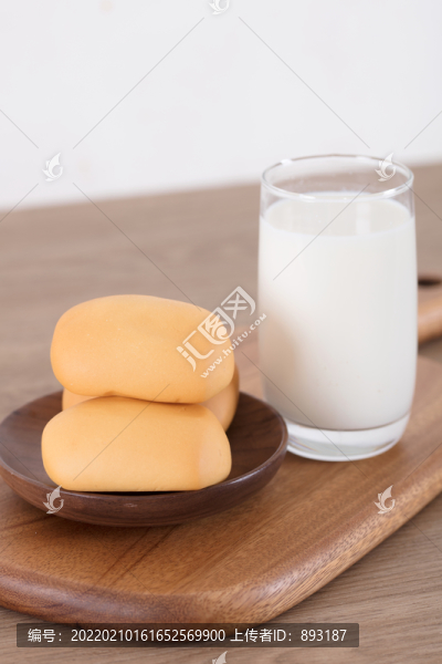 一杯牛奶和一些小面包在砧板上