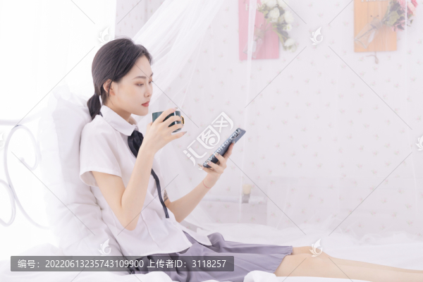 床上玩手機(jī)的年輕東方女性