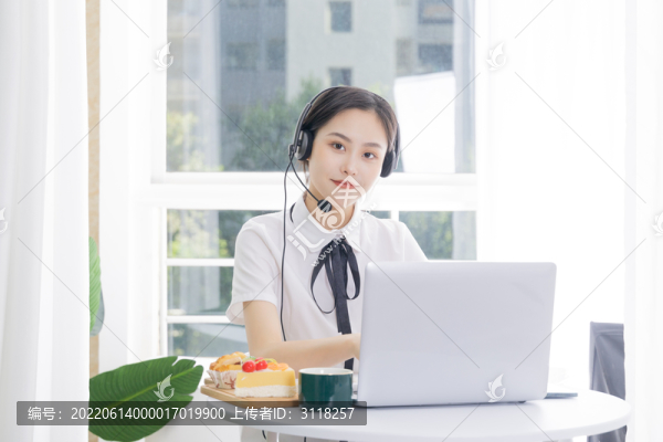 女性客服戴著耳麥?zhǔn)褂秒娔X