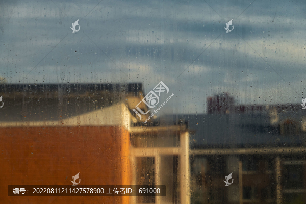 窗上雨痕后建筑上的陽光