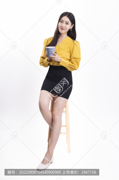 穿著黃色正裝拿著水杯的女性