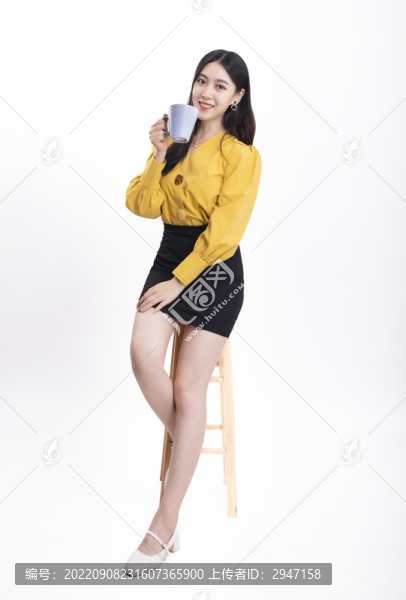 穿著黃色正裝拿著水杯的女性