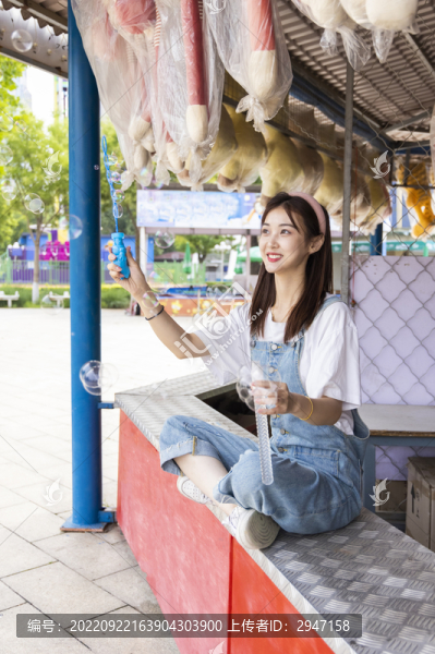 在游樂園里玩吹泡泡的美麗女孩