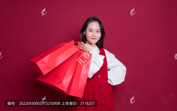紅色背景前手提購(gòu)物袋的女性
