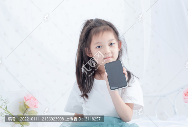 床上拿著手機(jī)的小女孩