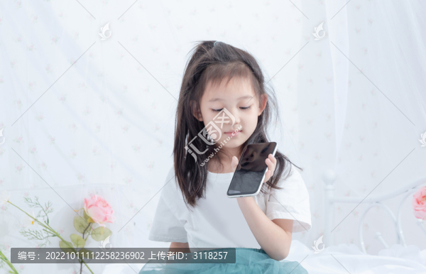 床上拿著手機的小女孩