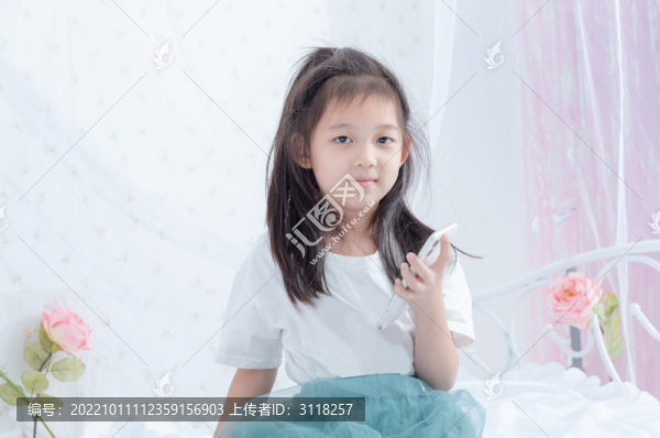 床上拿著手機的小女孩