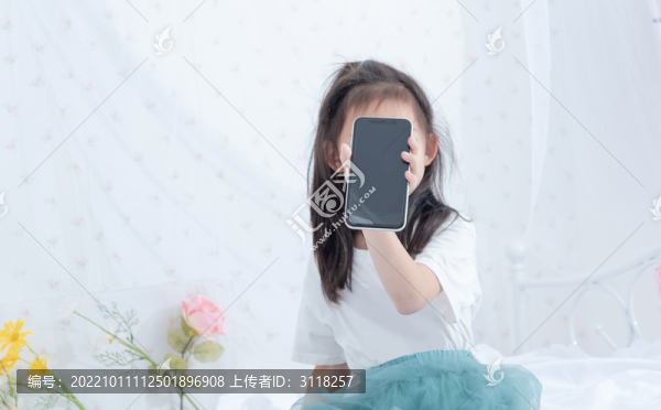 床上拿著手機的小女孩