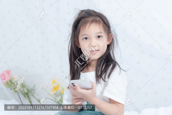 床上拿著手機的小女孩