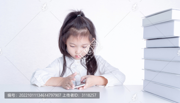 書桌上使用手機(jī)的小女孩