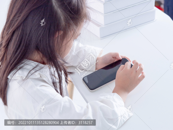 書(shū)桌上使用手機(jī)的小女孩俯視角