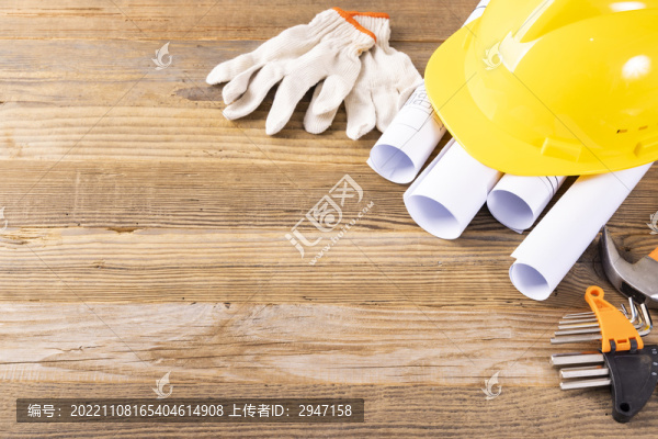 木桌上放著的安全帽和圖紙工具