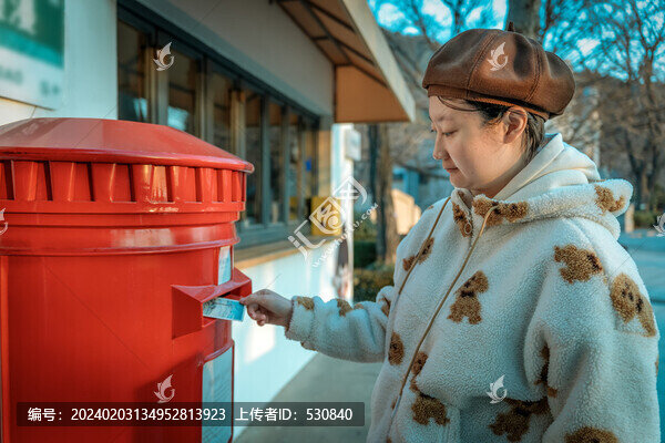 亚洲女孩在红色邮筒前投递明信片