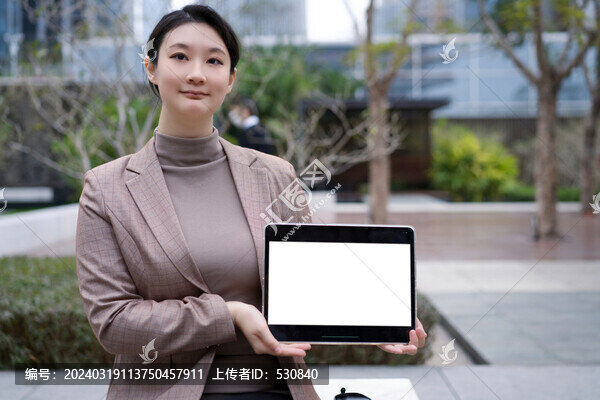 城市公園女子手拿空白筆記本電腦