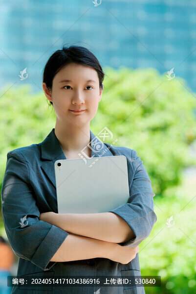 自信女性手持平板站在城市背景中