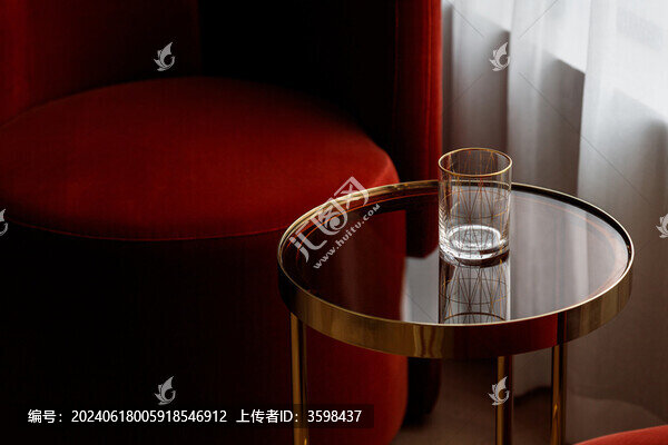 紅色沙發(fā)邊玻璃茶幾上透明玻璃杯