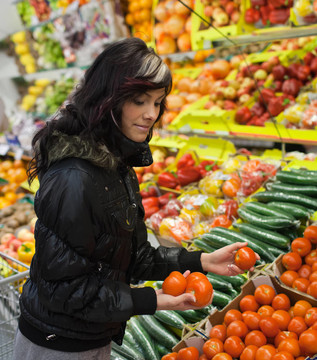 美丽的年轻女子在超市/杂货店买水果和蔬菜