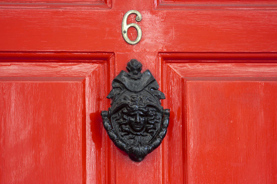 一个大红色的木制门，格鲁吉亚的门环