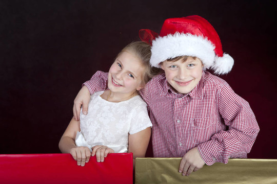 女孩和男孩在圣诞礼物在礼品盒
