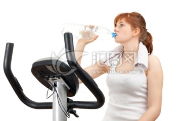 在固定训练自行车上锻炼的饮用水妇女