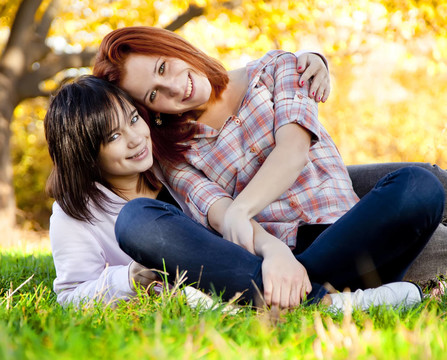 两个美丽的少女在公园里的绿草。