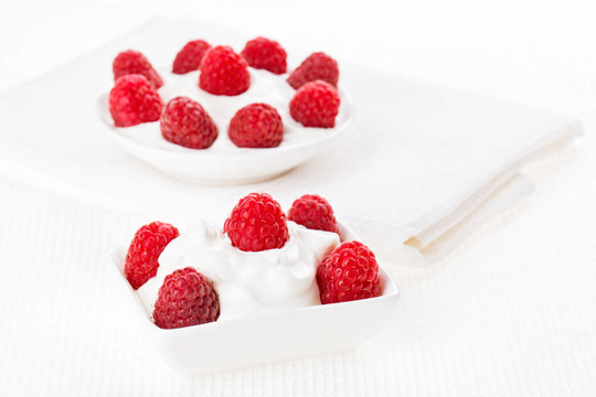 静物与树莓酸奶油甜点白色亚麻桌布；复制空间设计准备