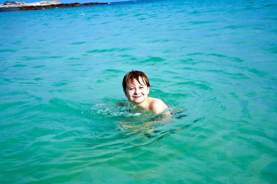 年轻的快乐男孩棕色头发喜欢游泳和玩美丽的大海