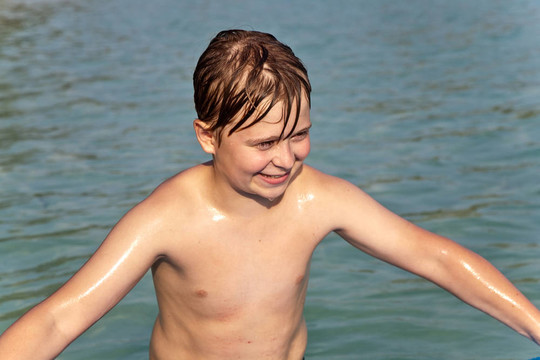 男孩冲浪在美丽的海边的一个小的冲浪板与清澈的水和蓝色的天空