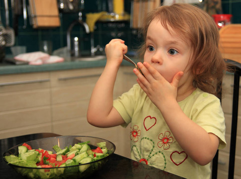 一个女孩吃蔬菜沙拉。