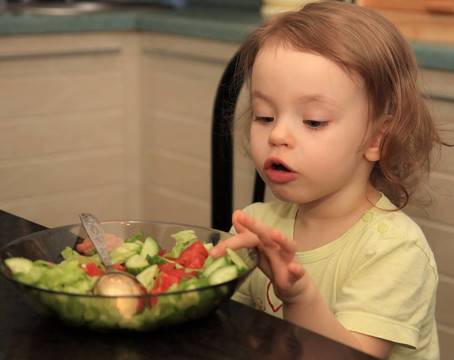 一个女孩吃蔬菜沙拉。