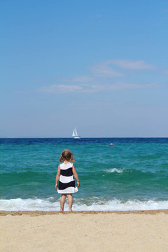 小女孩看着船在海上
