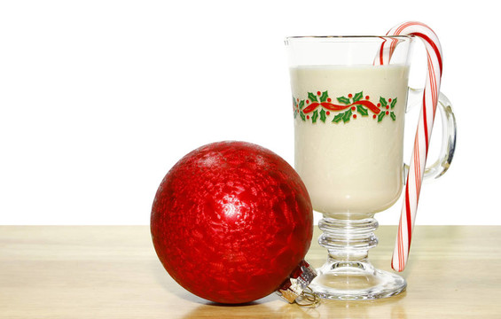一杯冷酒在一个木制的桌子和一个薄荷糖果和圣诞球沿着它为你的文本间的白色背景。