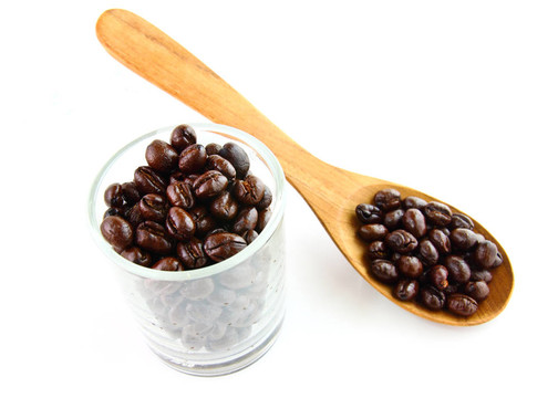 在白色背景上用汤匙放在玻璃杯里的咖啡豆