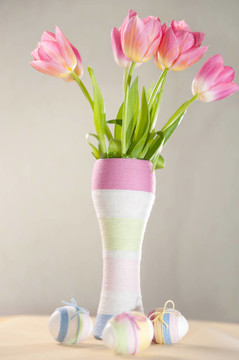 粉红色郁金香；复活节彩蛋和缠纱的瓶子