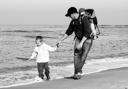 爸爸；儿子和女儿在海边散步，从波浪中奔跑