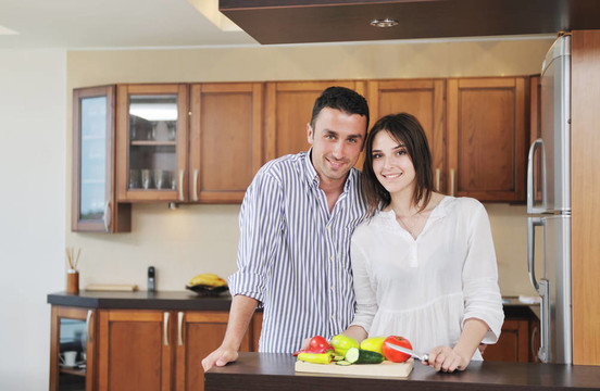 快乐的年轻夫妇在现代厨房里玩得开心