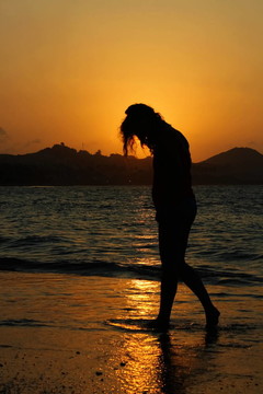 日落海滩上的剪影女人