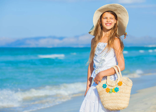 可爱的女孩在海滩上戴着优雅的帽子