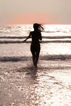 飘扬着头发的女孩的侧影；日落时分穿过海洋