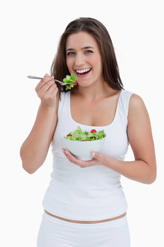 微笑的年轻女人在吃沙拉