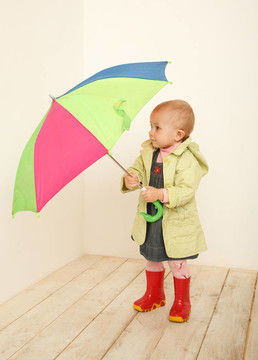 彩色的伞在她的手在外套的小女孩。看伞。室内的.