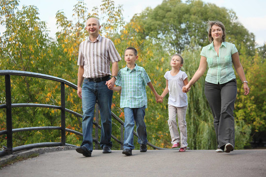 爸爸和女儿在初秋公园散步在桥上。家庭是情侣。
