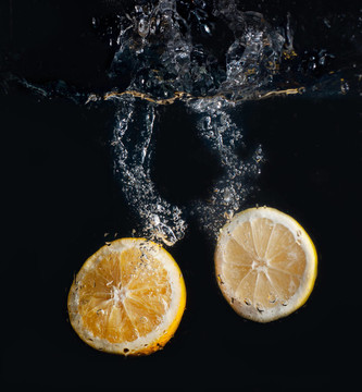 半柠檬和橘子在水中飞溅