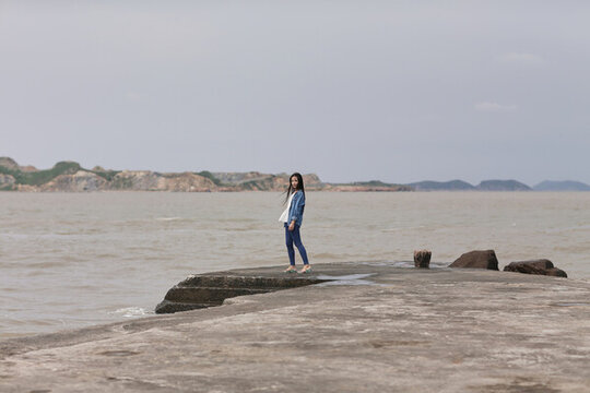 年轻女子站在码头看海