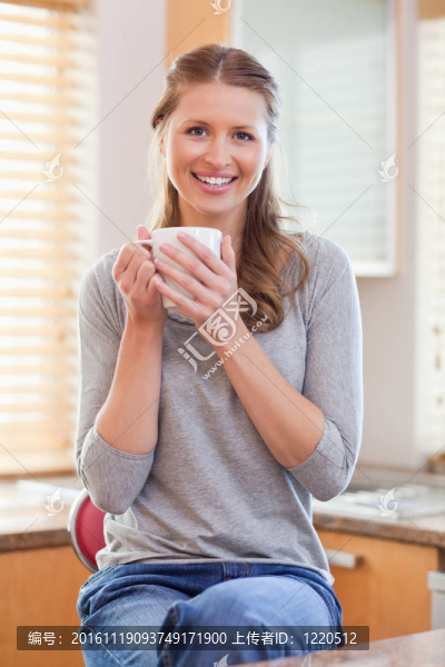 微笑的女人在厨房里喝咖啡