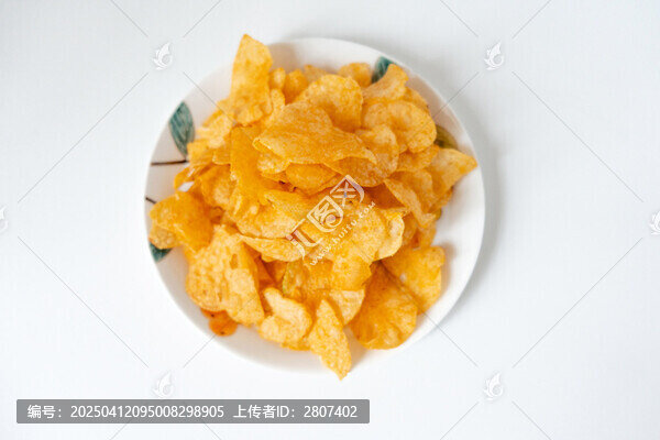 一盘白色彩绘碟子里装着一堆膨化薯片零食